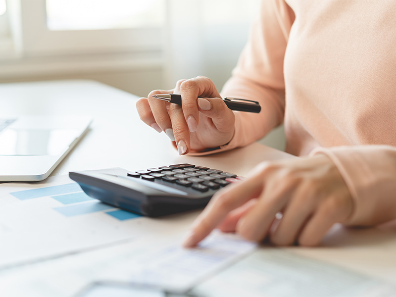 Frau berechnet Finanzen am Schreibtisch zur Steueroptimierung für Unternehmen, prüft Rechnungen, Einkommen und Ausgaben sorgfältig.